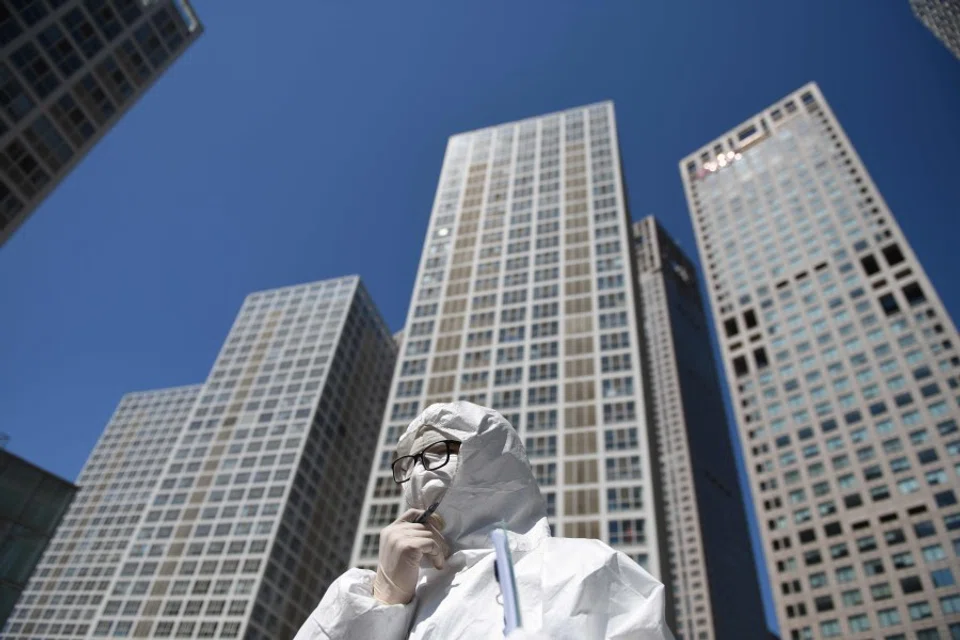 A worker in a protective suit waits to check the temperature of drivers at a commercial complex in Beijing, April 22, 2020. (Greg Baker/AFP)