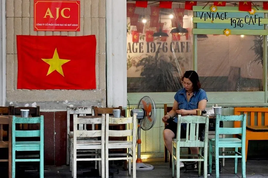 This photo taken on 3 June 2025 shows a woman using her phone at a cafe in Hanoi.