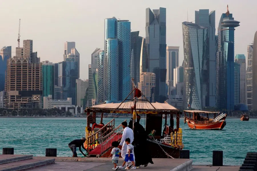 People walk next to an anchored traditional dhow boat are in front of the Doha skyline, Doha, Qatar, on 5 July 2025. (Karim Jaafar/AFP)