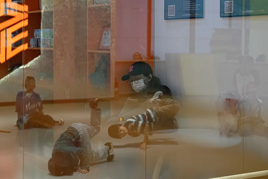 While Zhuangzhuang trains in a breaking class, his mother, Ran Xiaoqi, dozes off outside the classroom.