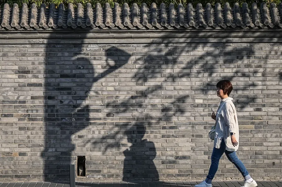 A woman walks along a street in Beijing on 8 May 2024.