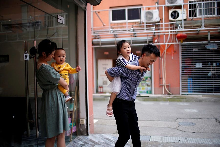A couple plays with their two children on the outskirts of Shanghai, China, 3 June 2021. (Aly Song/Reuters)