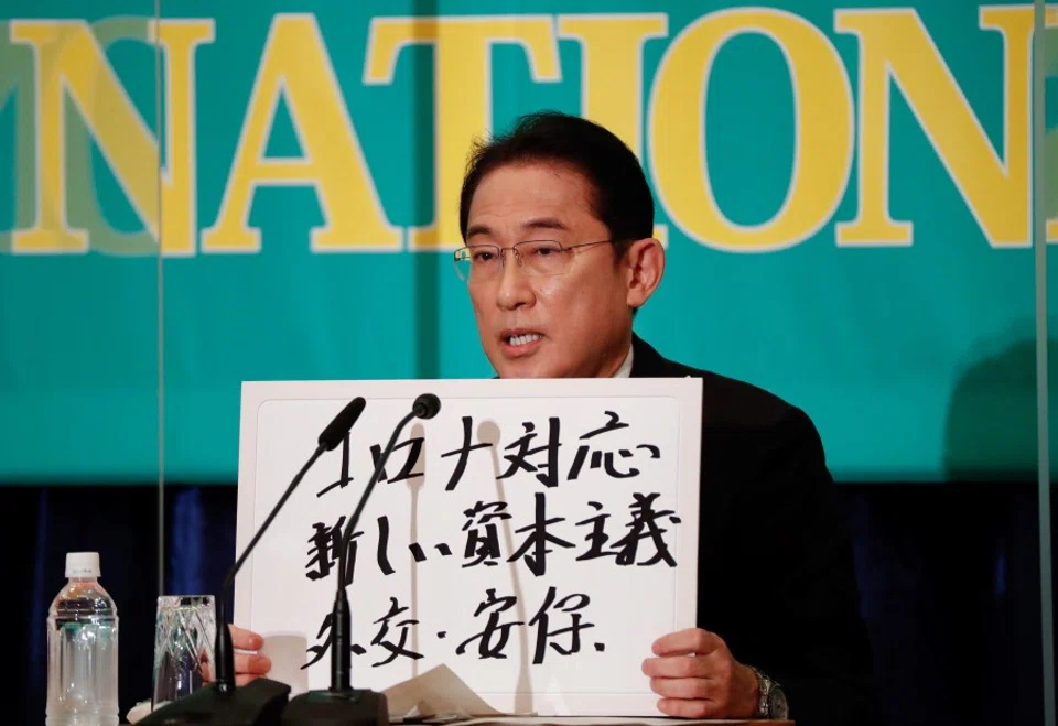 Japan's Prime Minister Fumio Kishida, who is also the president of the ruling Liberal Democratic Party, holds up a placard reading "Corona disease countermeasures, New Capitalism. Diplomacy and security" at a debate session with other leaders of Japan's main political parties ahead of the 31 October 2021 lower house election, at the Japan National Press Club in Tokyo, Japan, 18 October 2021. (Issei Kato/Reuters)