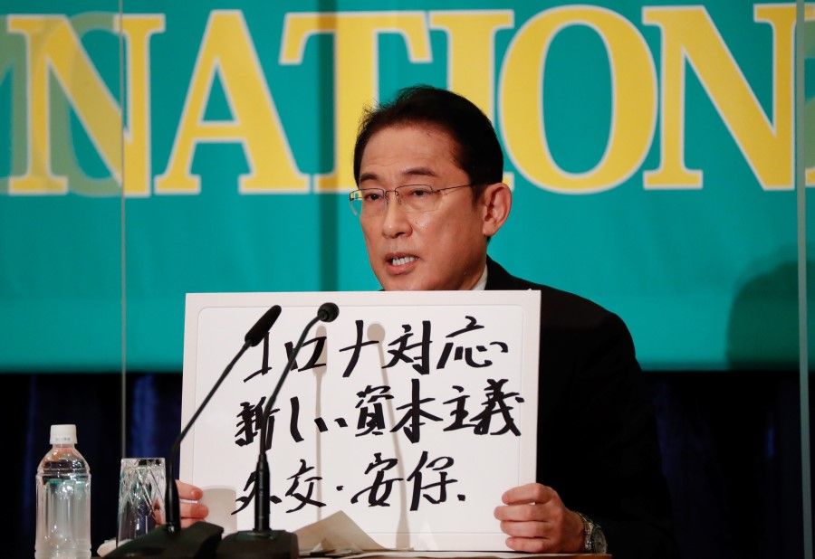 Japan's Prime Minister Fumio Kishida, who is also the president of the ruling Liberal Democratic Party, holds up a placard reading "Corona disease countermeasures, New Capitalism. Diplomacy and security" at a debate session with other leaders of Japan's main political parties ahead of the 31 October 2021 lower house election, at the Japan National Press Club in Tokyo, Japan, 18 October 2021. (Issei Kato/Reuters)