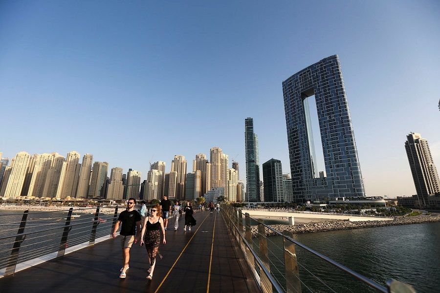 People walk on the pedestrian bridge at the Bluewaters Island in Dubai, United Arab Emirates, 8 December 2021. (Satish Kumar/Reuters)