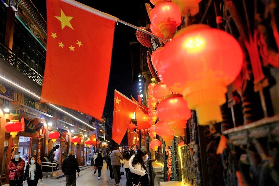 People wearing face masks walk near Qianmen Street, in Beijing, China, 10 February 2021. (Carlos Garcia Rawlins/Reuters)