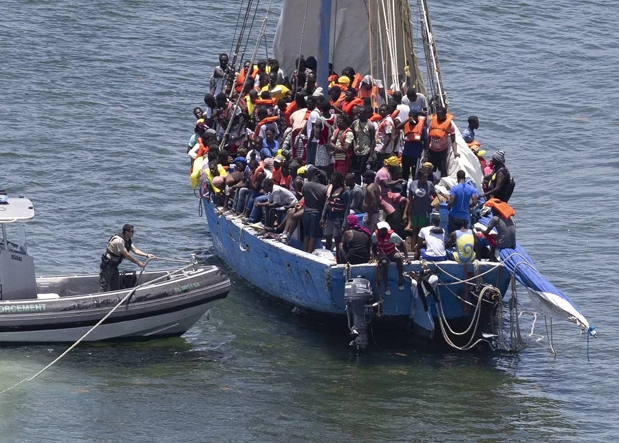 A FWC law enforcement officer helps people on a sailboat containing approximately 150 migrants on 21 July 2022 in Islandia, Florida, US. (Joe Raedle/Getty Images/AFP)