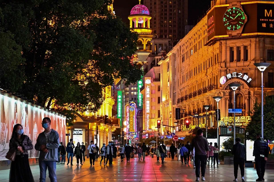 In this file photo taken on 12 October 2022, people walk along a pedestrian street surrounded by shops and shopping malls in Shanghai, China. (Hector Retamal/AFP)