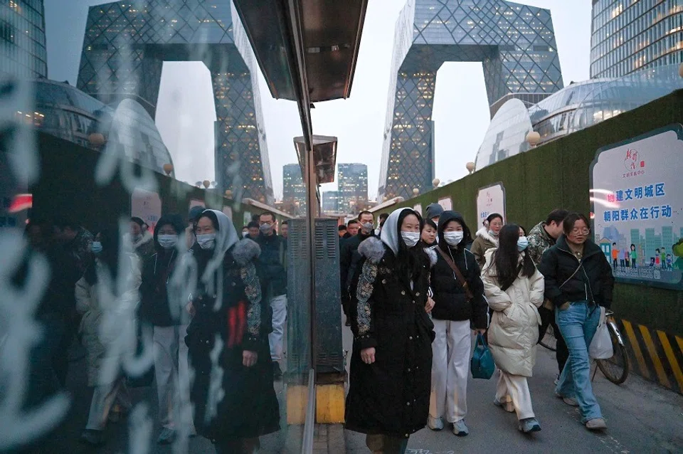 People walk on a sidewalk in the central business district in Beijing, China on 28 February 2024. (Greg Baker/AFP)