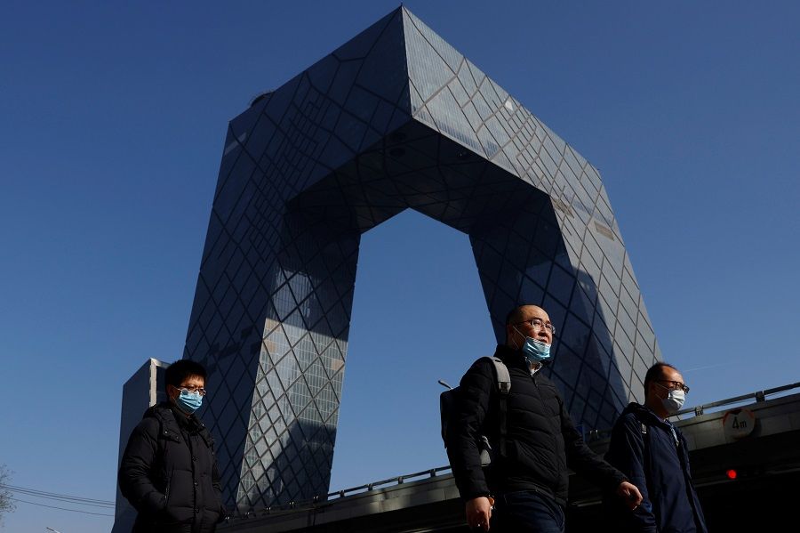 People wearing face masks walk past the CCTV headquarters, home of Chinese state media outlet CCTV and its English-language sister channel CGTN, in Beijing, China, 5 February 2021. (Carlos Garcia Rawlins/Reuters)