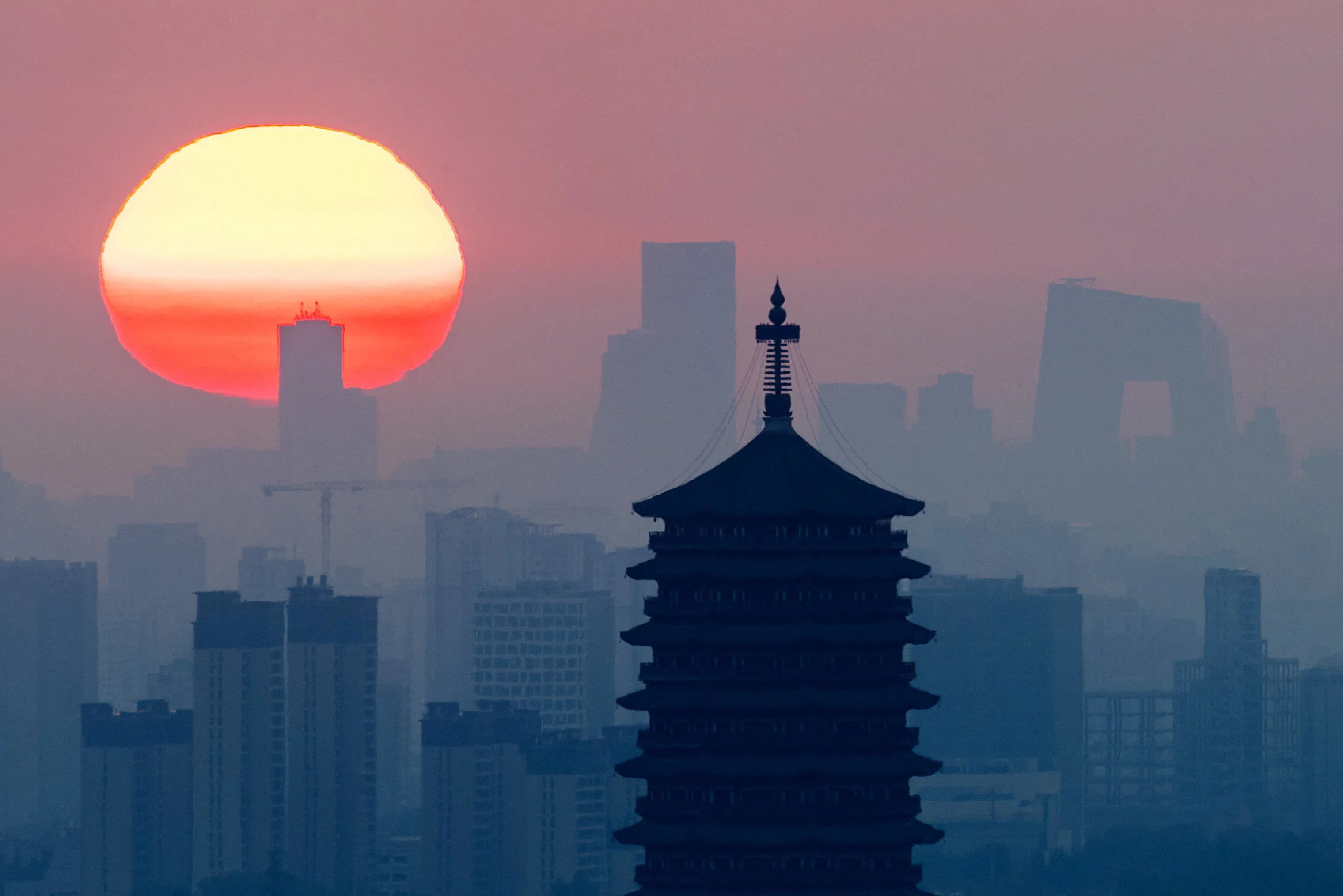 Yongding Pagoda stands against the rising sun and Beijing skyline, with skyscrapers in the central business district, including CCTV headquarters, seen in the distance, in Beijing, China, on 3 September 2026.