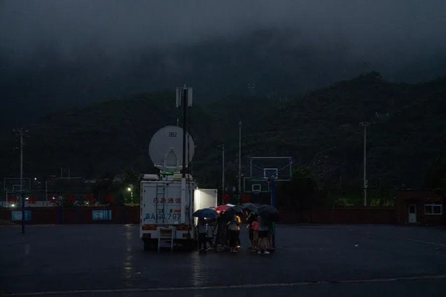 Villagers at Miaofengshan town charge their cell phones at a mobile telecommunication vehicle as the village is out of power on 1 August 2023.