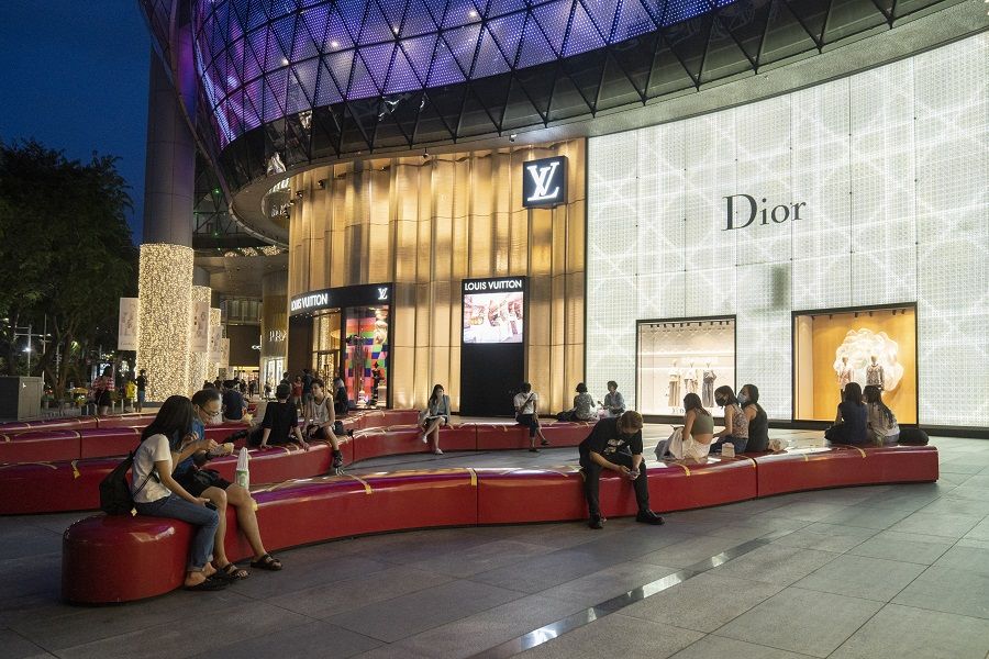 Visitors sit outside Ion Orchard mall on Orchard Road in Singapore on 22 January 2022. (Ore Huiying/Bloomberg)