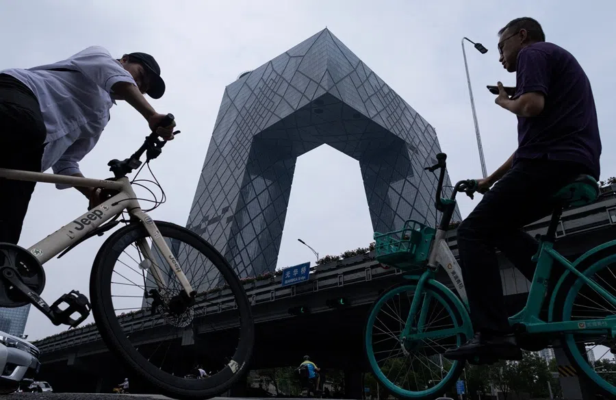 People ride bicycles next to CCTV Headquarters building in Central Business District (CBD) of Beijing, China, on 24 July 2026.