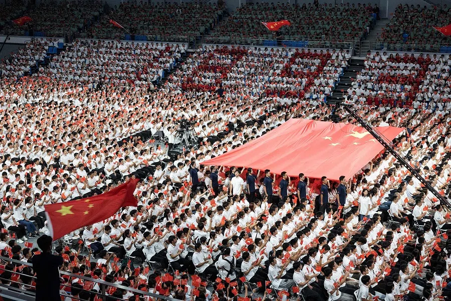 Students hold the national flag of China during an opening ceremony for undergraduates at the Wuhan University in Wuhan, Hubei province, China, on 12 September 2023. (AFP)