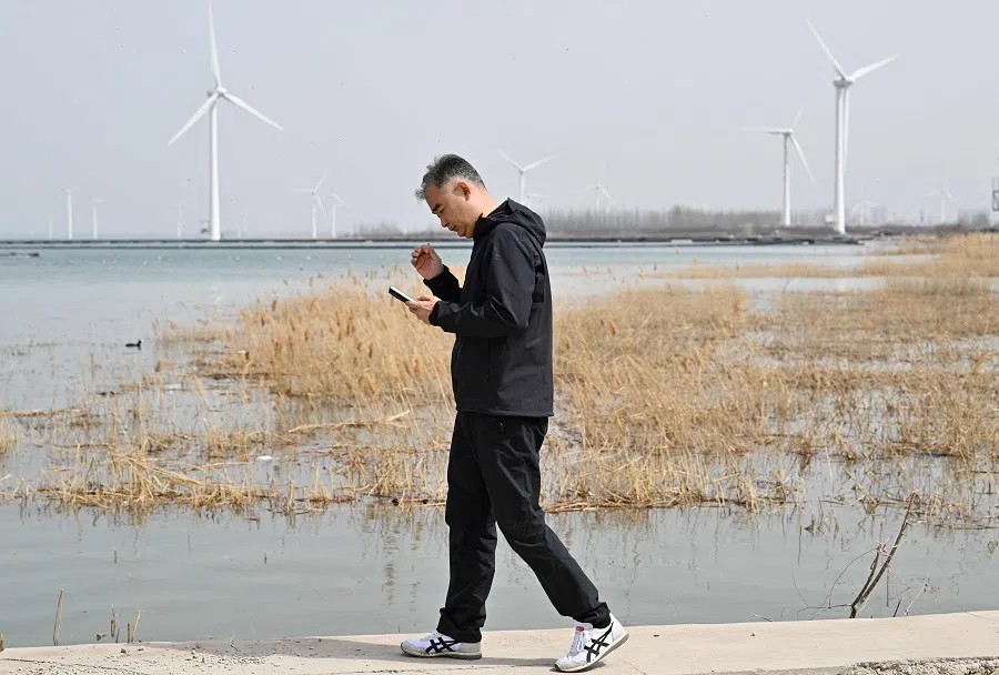 A man walks before wind turbines of Chinese company Goldwind in Zhangjiakou, northern China’s Hebei province on 26 March 2025. (Adek Berry/AFP)