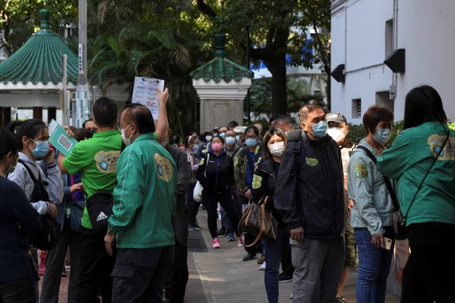 People wearing face masks line up outside a community vaccination centre to receive a dose of Sinovac Biotech's CoronaVac Covid-19 vaccine in Hong Kong, China, 2 December 2021. (Lam Yik/Reuters)