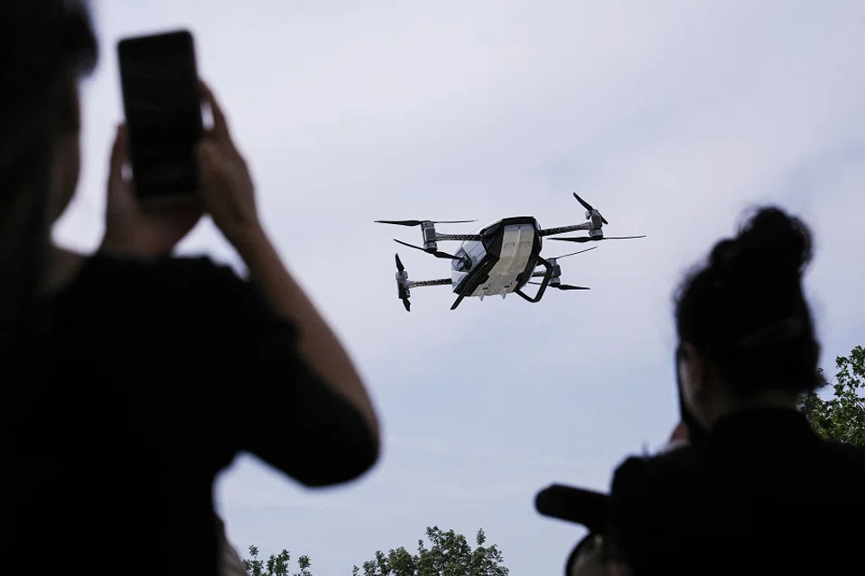 People look at the electric flying car XPeng Voyager X2 by XPeng Aeroht, as it takes off during a demonstration flight in Beijing, China, on 18 June 2024. (Tingshu Wang/Reuters)