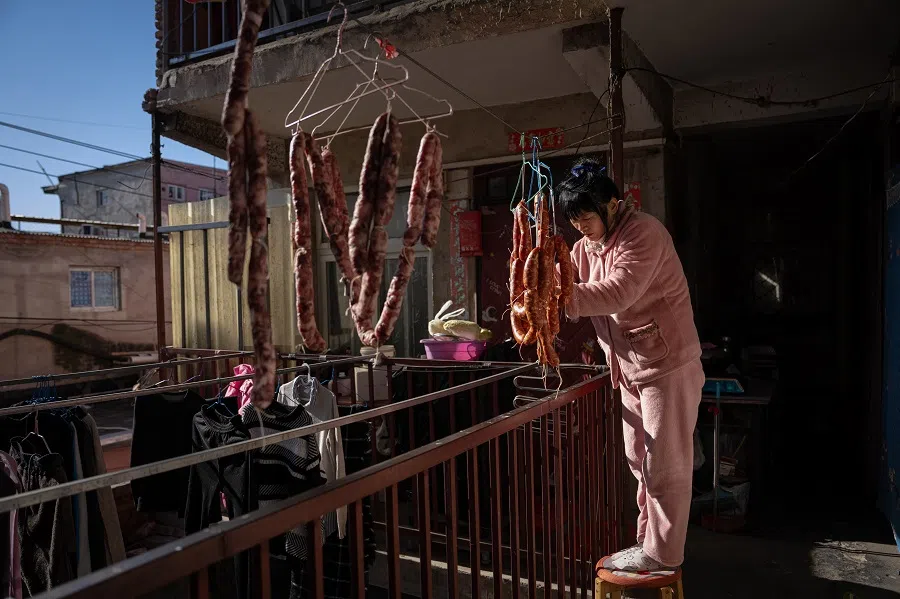 Sister Chen drying Chinese sausages outside her rented lodgings, in preparation to go home for Chinese New Year.