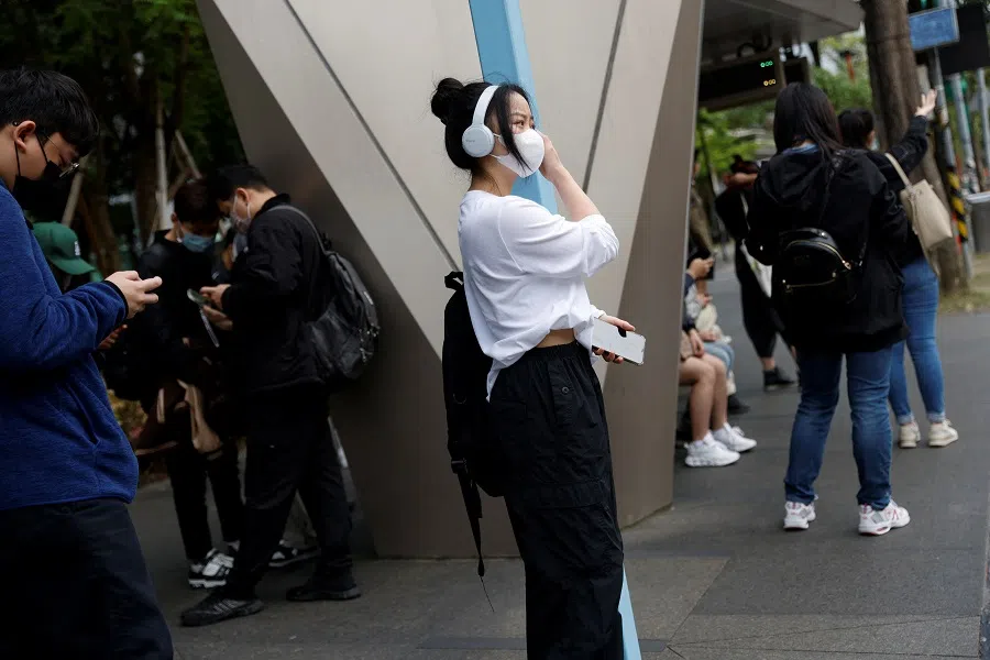 People wait for transport at a bus stop during morning rush hour in Taipei, Taiwan, 10 April 2023. (Carlos Garcia Rawlins/Reuters)