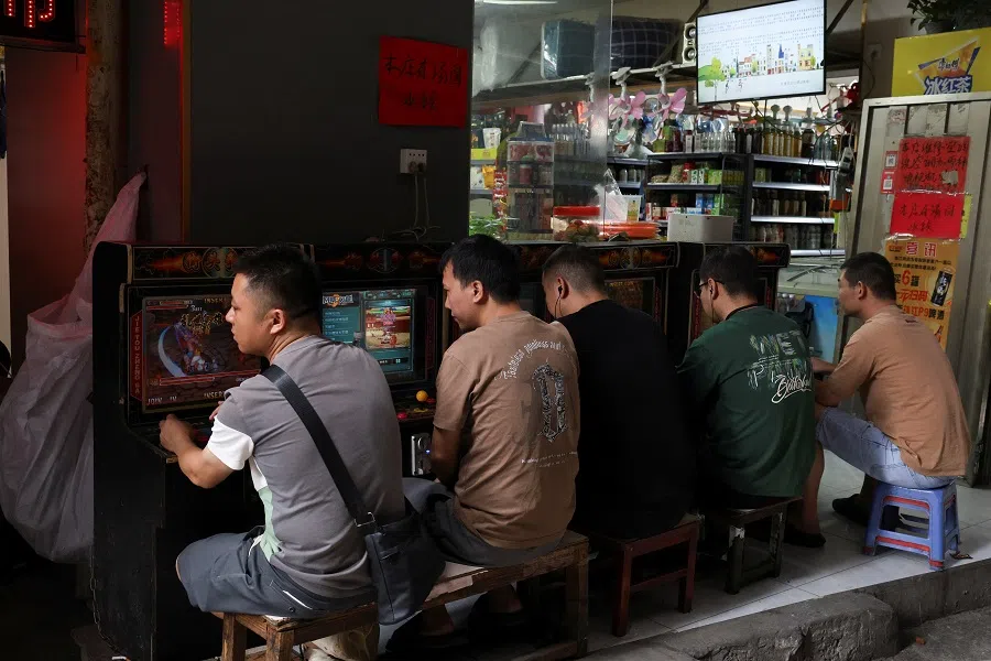 People play video games on a street in Datang Subdistrict, Guangzhou, Guangdong province, China on 10 May 2025. (Go Nakamura/Reuters)