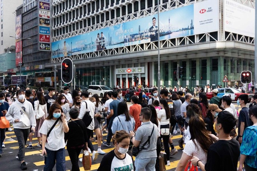 Pedestrians cross a street in Hong Kong on 31 October 2021. (Bertha Wang/AFP)