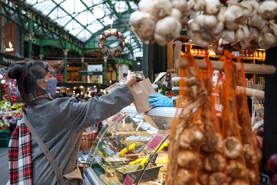 A customer purchases products from a vendor at Borough Market in London, UK, on 15 December 2021. (Hollie Adams/Bloomberg)