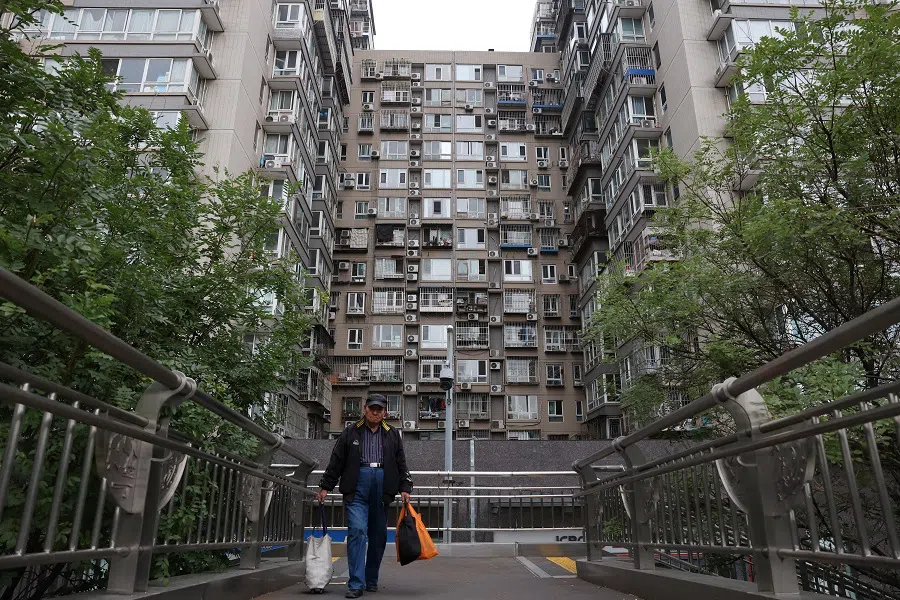 A man walks on a pedestrian bridge near residential buildings in Beijing, China, on 17 October 2024. (Florence Lo/Reuters)