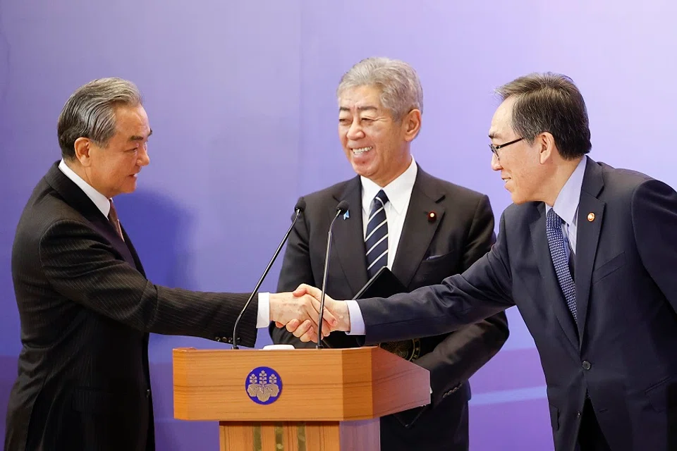 China’s Foreign Minister Wang Yi (left) and South Korea’s Foreign Minister Cho Tae-yul (right) shake hands as Japan’s Foreign Minister Takeshi Iwaya looks on during a joint press conference after their meeting during the 11th Trilateral Foreign Minister’s Meeting (Japan-China-ROK) in Tokyo on 22 March 2025. (Rodrigo Reyes Marin/AFP)