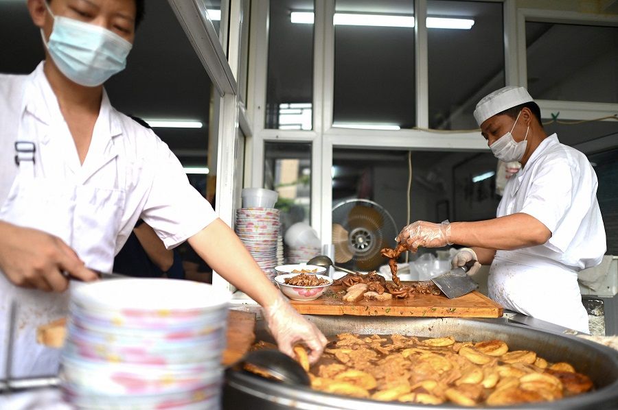 Cooks prepare a traditional Beijing street food, a pork stew with bread, at a restaurant in Beijing, China, on 3 August 2021. (Noel Celis/AFP)