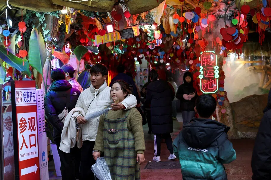 A couple walks out of a store entrance in Shanghai, China, on 14 February 2025. (Go Nakamura/Reuters)