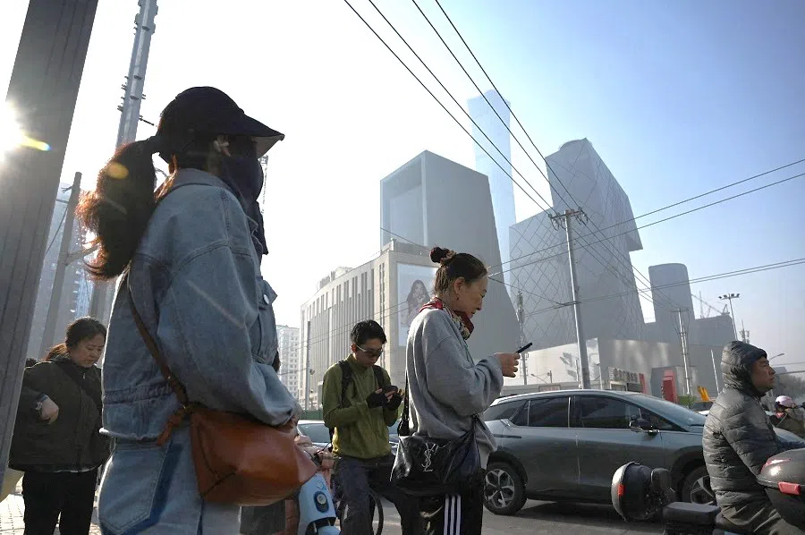 People wait to cross a road in Beijing’s central business district on 10 April 2025.