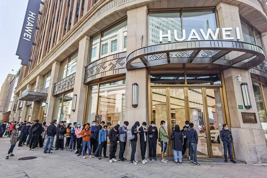 People wearing masks wait in line in front of Huawei's flagship store for pre-sales of the newly launched Huawei Mate 40 mobile phone series in Shanghai on 23 October 2020. (STR/AFP)