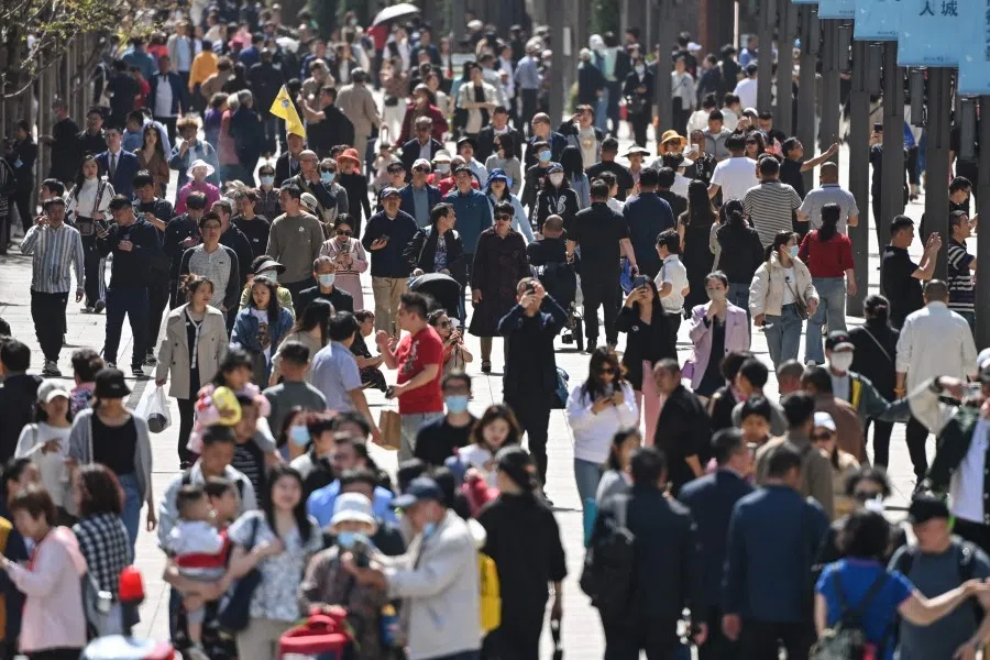 People walk on a street in Shanghai on 21 April 2023. (Hector Retamal/AFP)