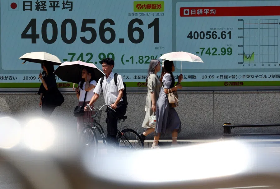 People walk in front of a screen displaying Japan’s Nikkei share average in Tokyo, Japan, on 4 August 2025. (Issei Kato/Reuters)