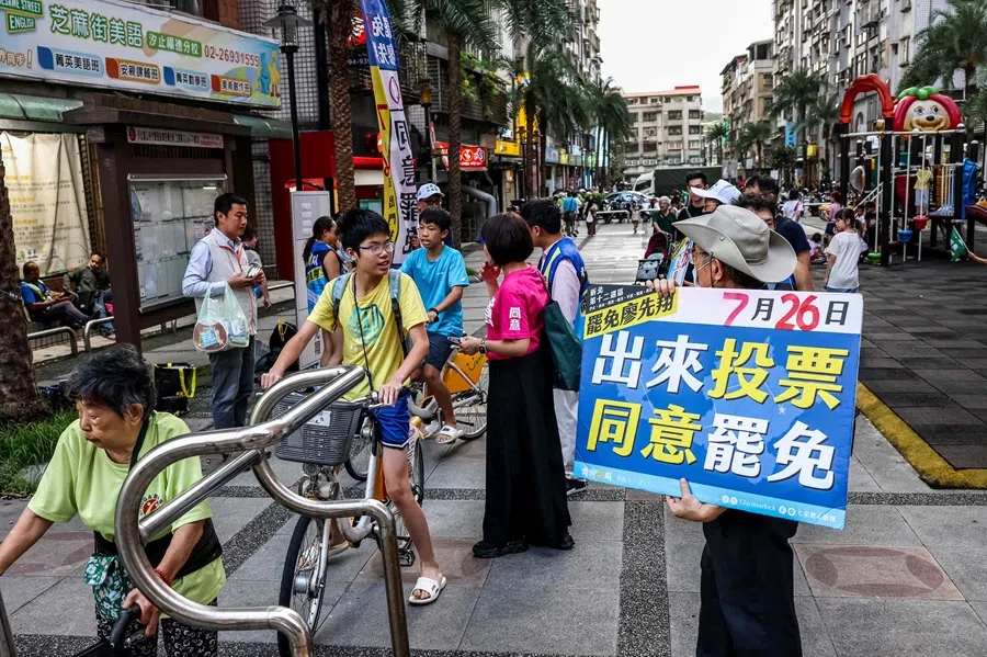 A supporter of the recall election holds a banner for canvassing at a local park in New Taipei City on 24 July 2025. (I-Hwa Cheng/AFP)