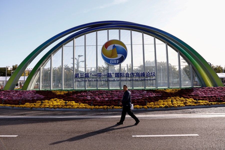 A person walks past a sign of the Third Belt and Road Forum ahead of its opening ceremony, at the media centre in Beijing, China, on 18 October 2023. (Tingshu Wang/Reuters)