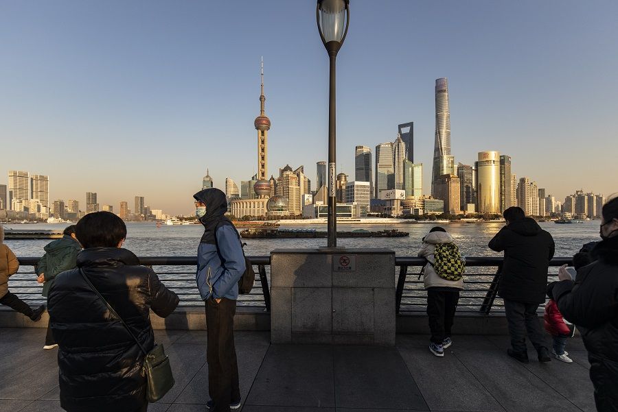 Pedestrians walk along the Bund past buildings in the Lujiazui Financial District across the Huangpu River in Shanghai, China, on 28 December 2021. (Qilai Shen/Bloomberg)