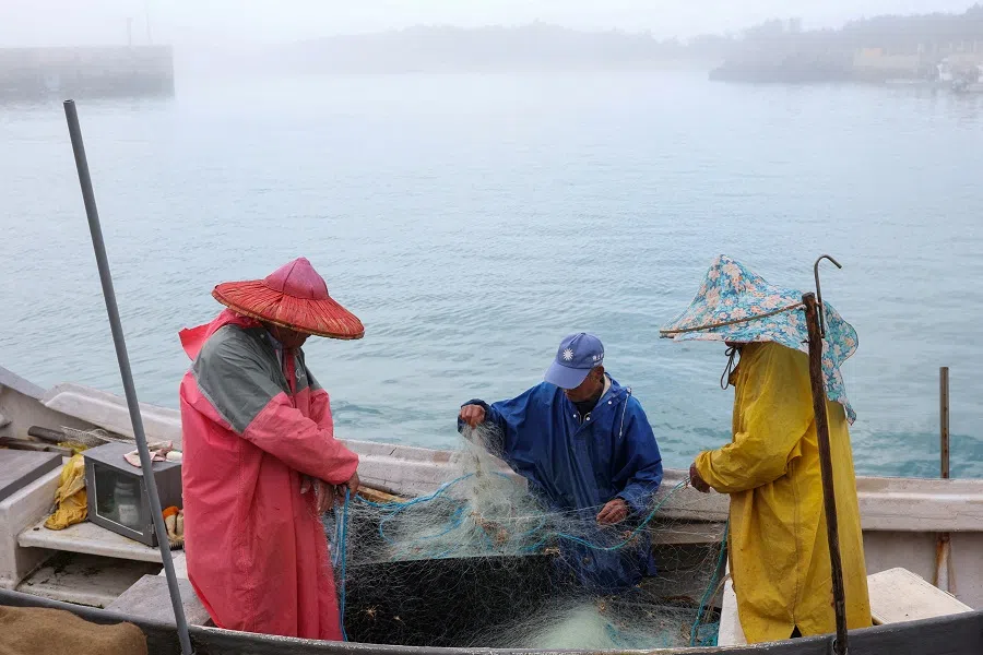 Fishermen work on their boat docked at a port in Kinmen, Taiwan, on 21 February 2024. (Ann Wang/Reuters)
