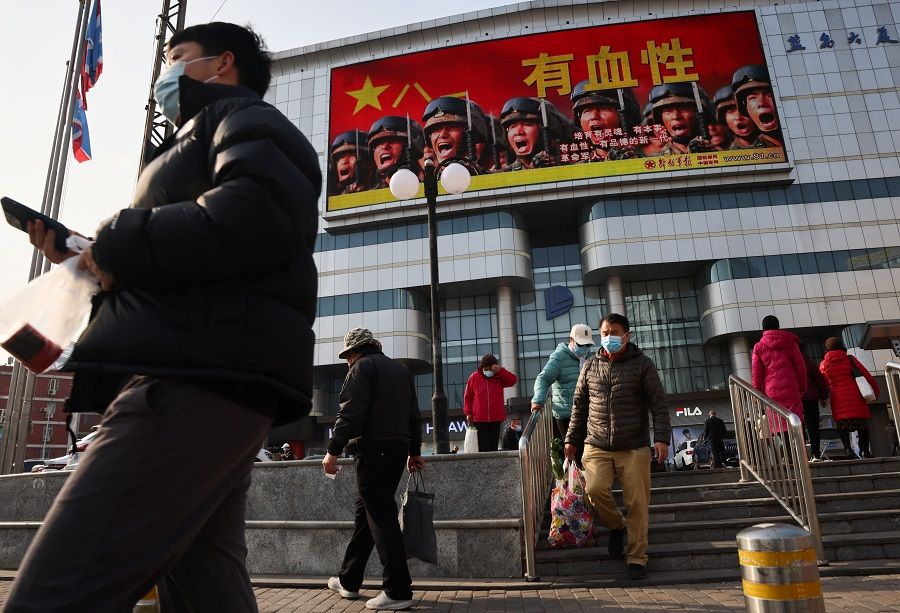An advertisement of the People's Liberation Army overlooks a street scene in Beijing, China, 16 November 2021. (Thomas Peter/Reuters)