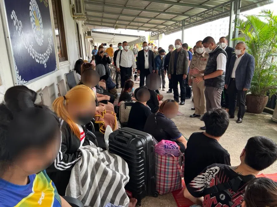 Thai police standing in front of some Thai nationals allegedly enslaved by scam gangs based in Cambodia. This picture was taken in Cambodia. (Tan Hui Yee/SPH Media)