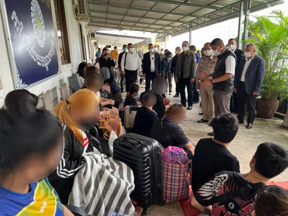Thai police standing in front of some Thai nationals allegedly enslaved by scam gangs based in Cambodia. This picture was taken in Cambodia. (Tan Hui Yee/SPH Media)