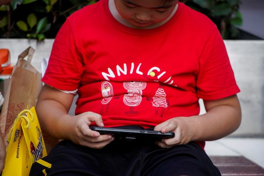 A boy plays a game on a phone on a street in Shanghai, China, 31 August 2021. (Aly Song/Reuters)