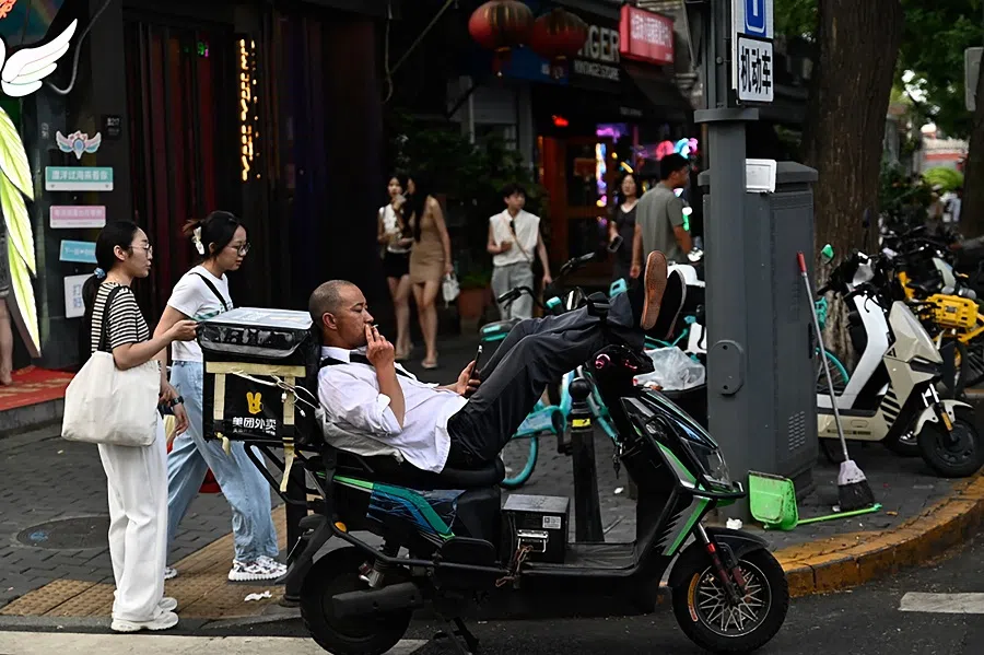 A delivery worker rests at a tourist area in Beijing, China,11 August 2024. (Pedro Pardo/AFP)