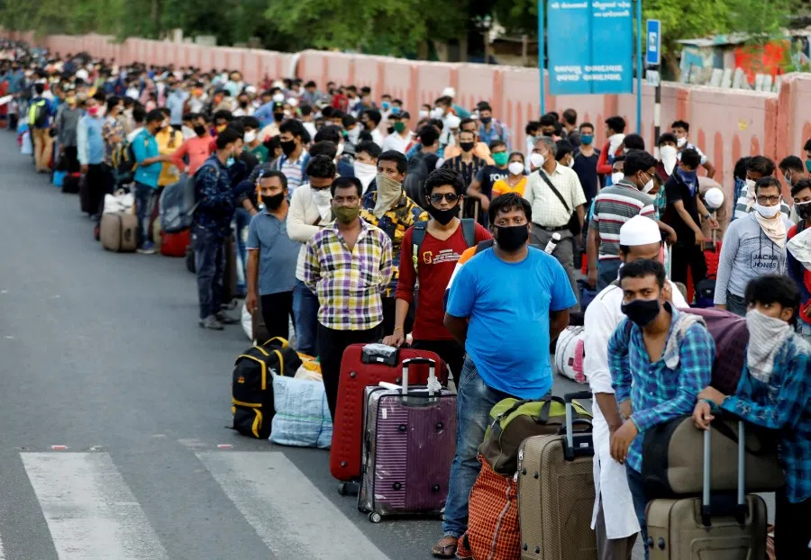 Migrant workers and their families wait in lines outside a railway station to board a train to their home state of West Bengal, in Ahmedabad, India, 18 June 2020. (Amit Dave/REUTERS)