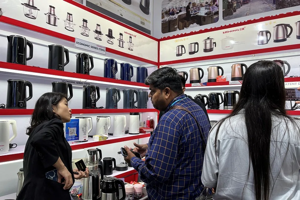 A staff member attends to visitors at a kettle retailer at the China Import and Export Fair, also known as Canton Fair, in Guangzhou, Guangdong province, China, 16 April 2023. (Ellen Zhang/Reuters)