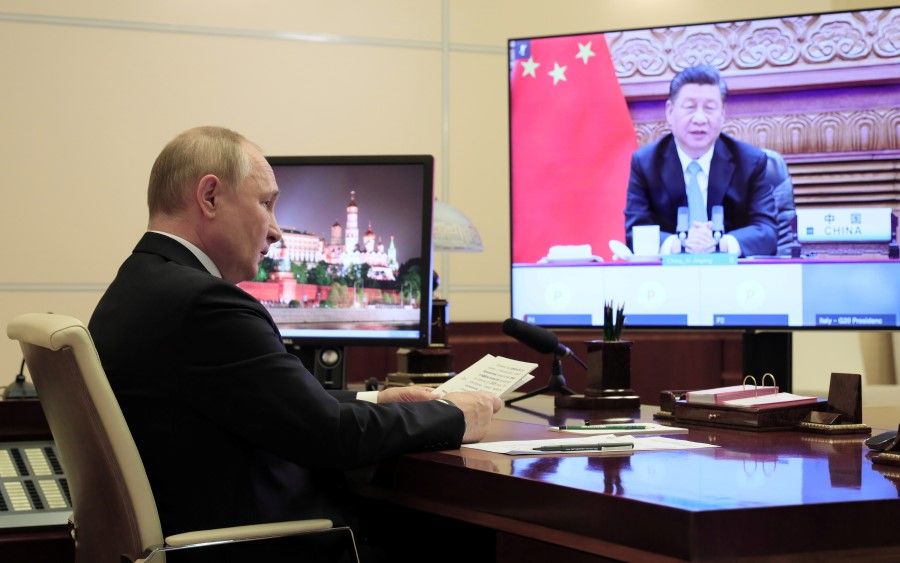 Russian President Vladimir Putin sits in front of a screen displaying Chinese President Xi Jinping as he attends the G20 summit via a video link at his residence outside Moscow, Russia, 31 October 2021. (Sputnik/Evgeniy Paulin/Kremlin via Reuters)