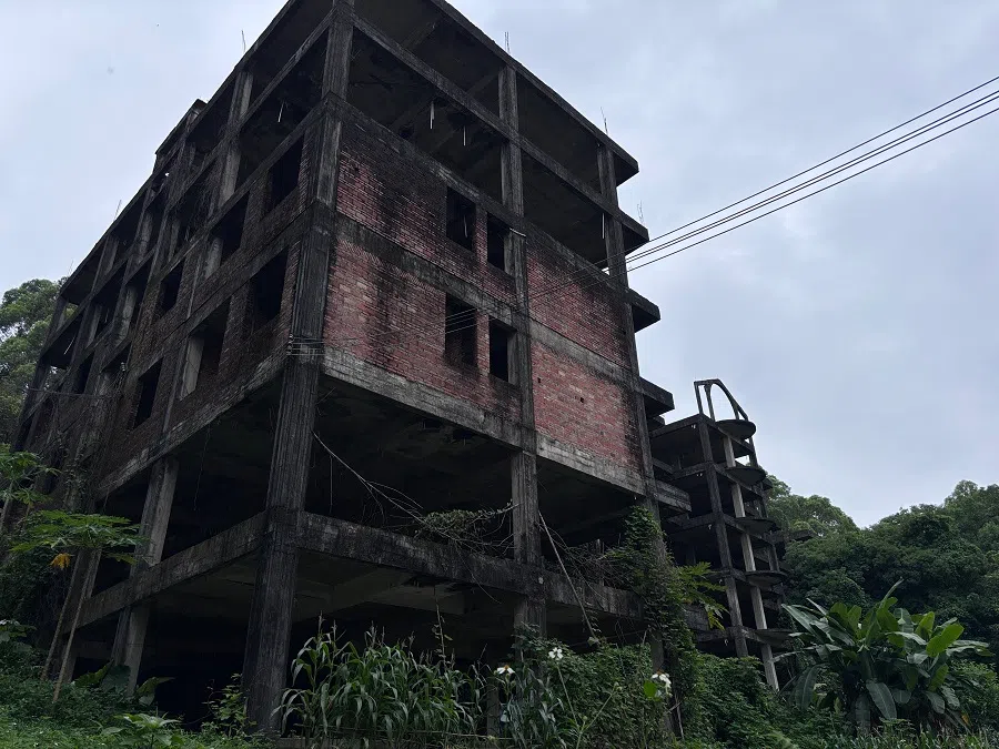 On the upper half of the hill, an incomplete Australia Garden Village building wastes away. 