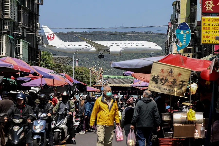 A Japan Airlines passenger plane lands as people visit a market in Taipei on 20 March 2025.