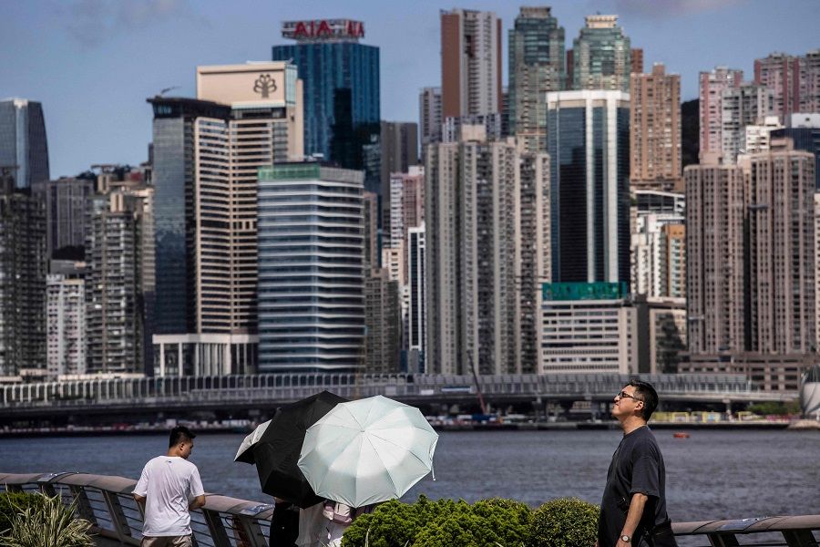 People walk along a promenade along Victoria Harbour in Hong Kong, China, on 11 July 2023. (Isaac Lawrence/AFP)